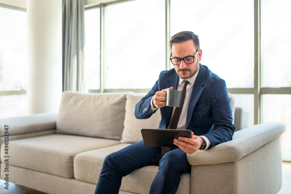 Young man drinking coffee and reading news on his tablet