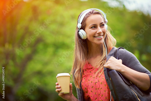 Take your music and coffee with you. Shot of a young woman listening to music while having a coffee on the go.