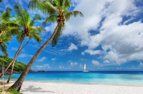 Sunny beach with Coco palms and a sailing boat in the turquoise sea in Paradise island.	 photo