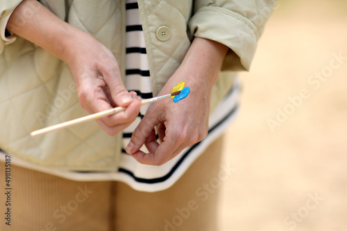 Stop War. Peace in Ukraine. woman drawing picture of flag of ukraine on hand. Antiwar support concept. High quality photo