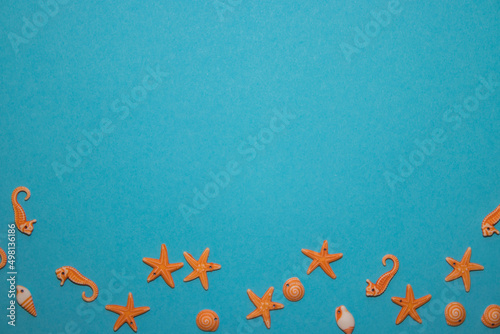 Turquoise background with seashells in the shape of starfish and seafood with empty space in the middle.