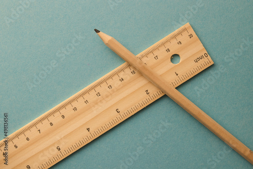 A pencil and ruler lying on the turquoise background in the middle