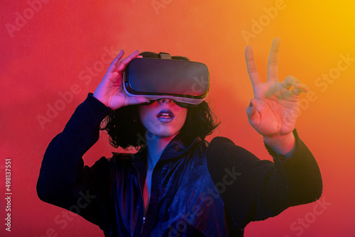 The young woman is using virtual reality viewer. Modern woman portrait with trendy look and bright colors.