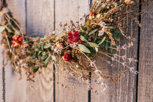 Close up photo, part of twisted crafting, arvensis creative dry herbal wreath from twigs of wild flowers, cereal and grass. Traditional festive ethnic decoration on entrance door. Low angle view