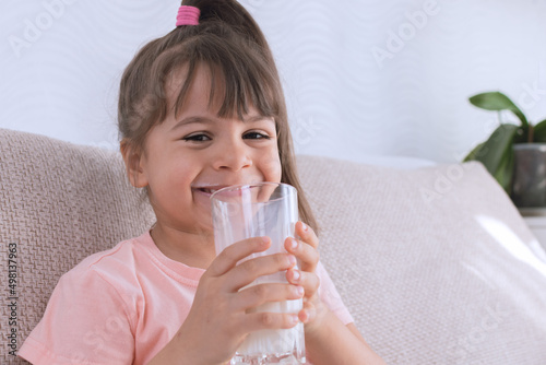 Little girl child drinking milk. healthy eating a child eating breakfast kid dream concept. daughter girl in kitchen drinks yogurt milk.