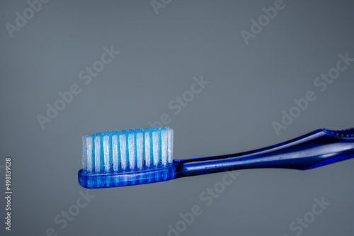 Budget toothbrush blue. Brush on a gray background. Cleaning tool.