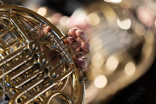 A person playing a French horn during a concert. An instrument from the brass section.