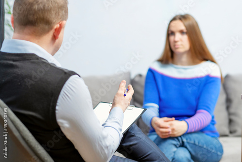 Fototapeta Naklejka Na Ścianę i Meble -  Professional help. The psychologist professional is talking to a client. The psychologist with clipboard taking notes and listening to female patient in psychotherapy session