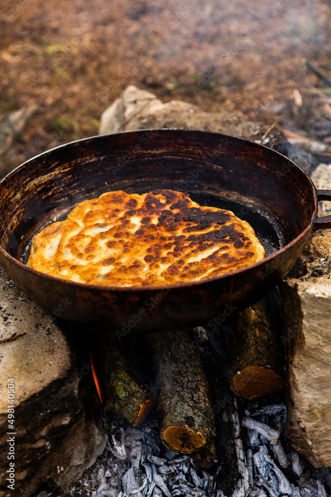 Romanian traditional pie with cheese cooked on a pan on the fire outside. Food from Romania and Republic of Moldova. Romanian traditional pie with cheese cooked on a pan on the fire outside. Food from Romania and Republic of Moldova.