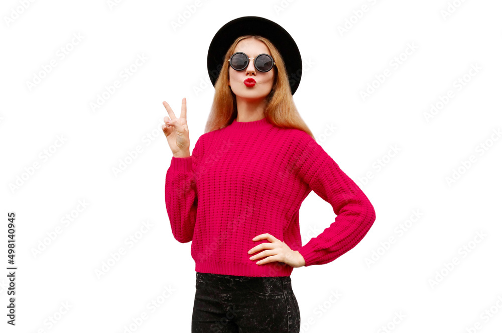 Portrait of beautiful young woman model blowing her red lips wearing pink knitted sweater and black round hat isolated on white background Portrait of beautiful young woman model blowing her red lips wearing pink knitted sweater and black round hat isolated on white background