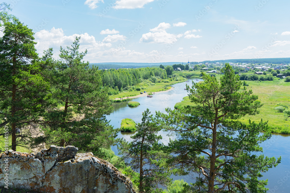 View of the Chusovaya river through trees and rocks on a sunny summer day, Ural, Sverdlovsk region, Russia
