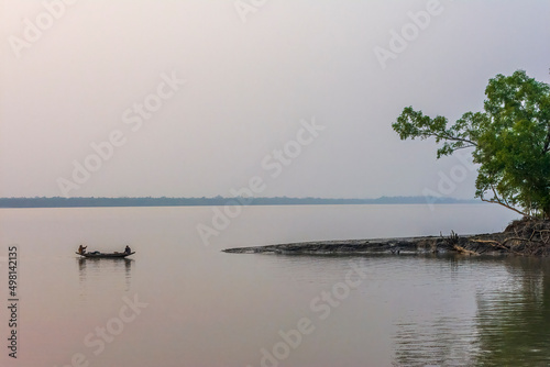 Fishermen fishing on a country boat in the dusk, on a river, in Bangladesh Sundarbans