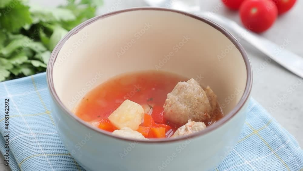 Soup with tomatoes and meatballs. Filling a bowl with hot, delicious freshly cooked delicious soup. Soup with tomatoes and meatballs. Filling a bowl with hot, delicious freshly cooked delicious soup.