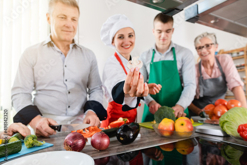 Dietician showing her trainees how to cook healthily with vegetables und such stuff, but way too little meat or candy