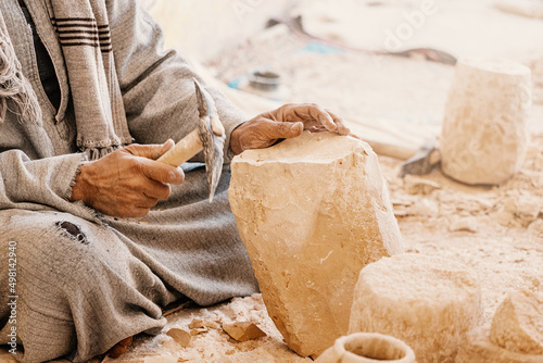 A worker or craftsman works with a pickaxe hammer to process stone