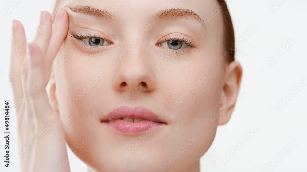 Big close-up shot of young European woman looks at camera stretching her skin on white background | Ptosis prevention concept Big close-up shot of young European woman looks at camera stretching her skin on white background | Ptosis prevention concept