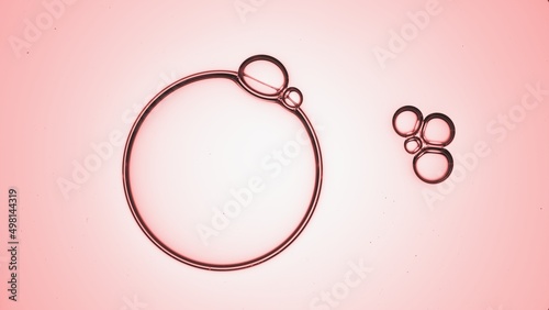 Macro shot of big clear bubble small ones floating in transparent liquid on on pale pink background | Skincare cream ingredients commercial