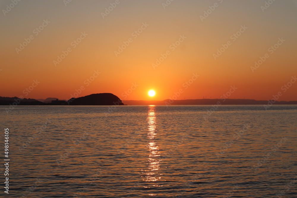 遠くに沈む夕日が海に映る風景
