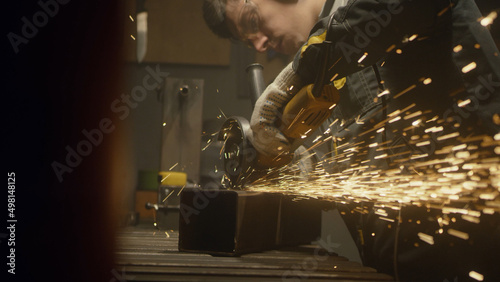A man works with a circular saw. Worker grinder grinds metal in workshop. Sparks fly from hot metal. The man worked hard on the steel. Close-up slow motion in the garage