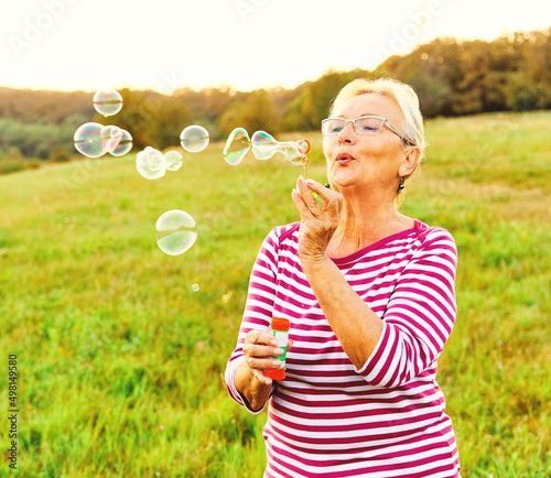 Canvas-taulu woman outdoor senior elderly happy fun retirement vitality bubble soap blowing a