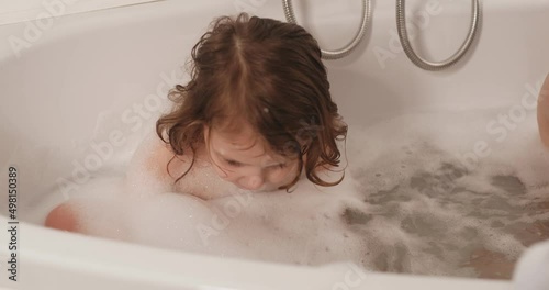 The twin girls take a bath in the evening, playing on their own. photo