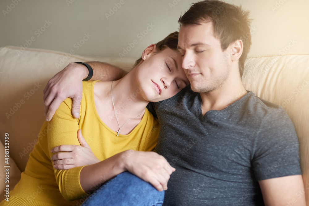 True love means being there for one another. Shot of a tired couple cuddling together on the couch at home. True love means being there for one another. Shot of a tired couple cuddling together on the couch at home.