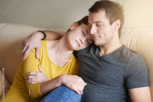 True love means being there for one another. Shot of a tired couple cuddling together on the couch at home.