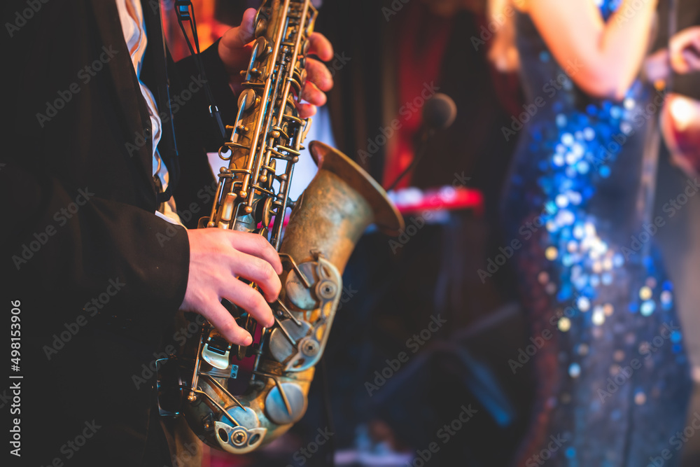 Concert view of a saxophonist, saxophone sax player with vocalist and musical during jazz orchestra performing music on stage - obrazy, fototapety, plakaty 
