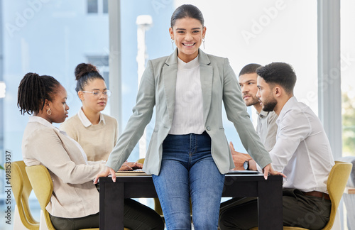 You wont find a team more exceptional than mine. Portrait of a young businesswoman standing in an office while her colleagues have a meeting in the background.
