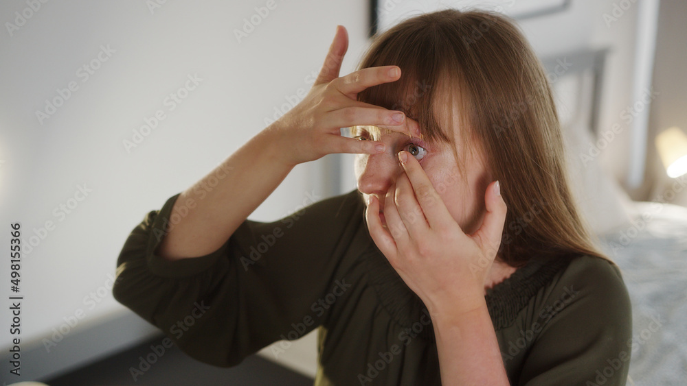 Closeup indoor shot of a young caucasian woman putting in contact lenses near mirror. High quality photo Closeup indoor shot of a young caucasian woman putting in contact lenses near mirror. High quality photo