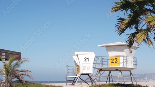 Lifeguard stand and palm tree, life guard tower for surfing on California beach. Summer pacific ocean in USA aesthetic. Iconic rescue baywatch station, coast lifesavers wachtower hut or house by sea. photo