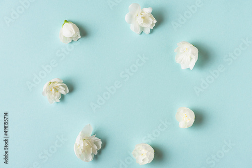 Flower composition. Frame made of white jasmine flowers on pastel blue background with copy space. Flat lay