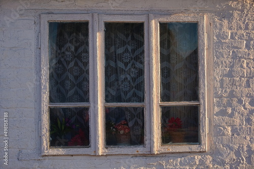 window of the old house and a wall of white brick
