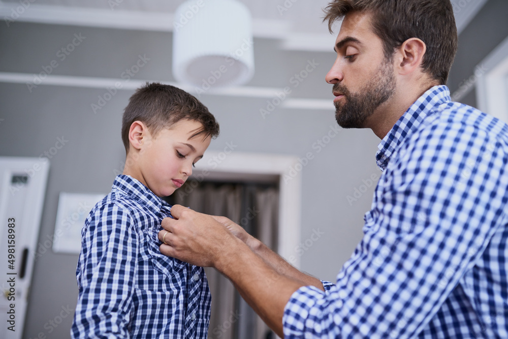 Let me help you with that button. Cropped shot of a handsome young man and his son getting dressed in the morning. Let me help you with that button. Cropped shot of a handsome young man and his son getting dressed in the morning.