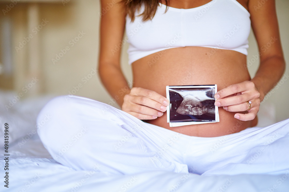 Shes excited about her little one. Shot of a pregnant woman holding a sonogram picture in front of her belly. Shes excited about her little one. Shot of a pregnant woman holding a sonogram picture in front of her belly.