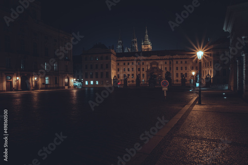 view of street lights and tiled streets and in the background prague castle at night in the center of the old town of prague