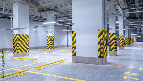Empty shopping mall underground parking lot or garage interior with concrete stripe painted columns