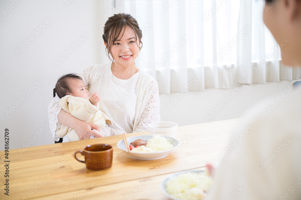 Mom eating dinner with her baby at the dining table, smiling. Copy space available on the right.