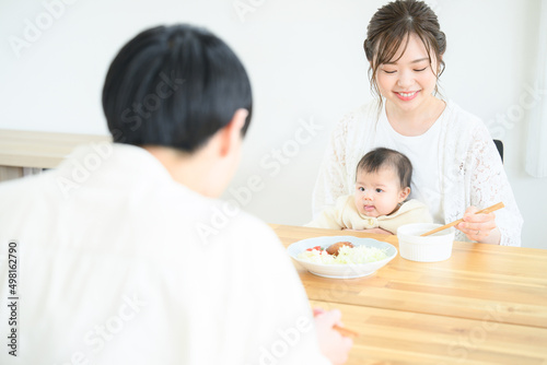 食卓で赤ちゃんと一緒にご飯を食べるママさん　笑顔　左にコピースペースあり