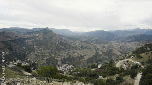 Top view of mountain valley with small village. Action. Beautiful landscape of mountain valley on summer day. Mountain valley with village on cloudy day