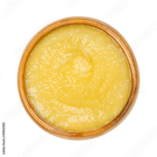 Apple sauce in a wooden bowl. Commercially processed applesauce, a yellow sauce made of peeled and cooked apples. Inexpensive and widely consumed in North America and parts of Europe. Macro food photo