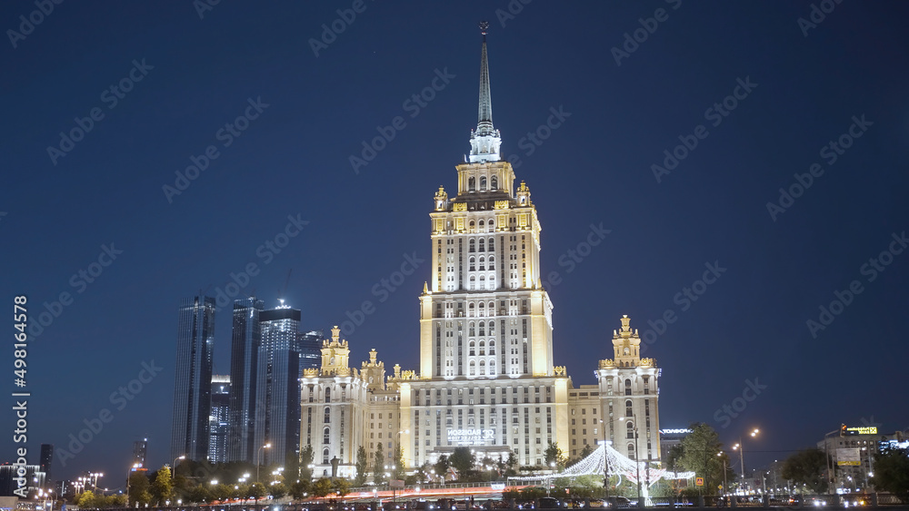 Late night cityscape with illuminated skyscraper in Moscow designed in the Stalinist style. Action. Beautiful building on a dark blue evening sky background, concept of architecture.
