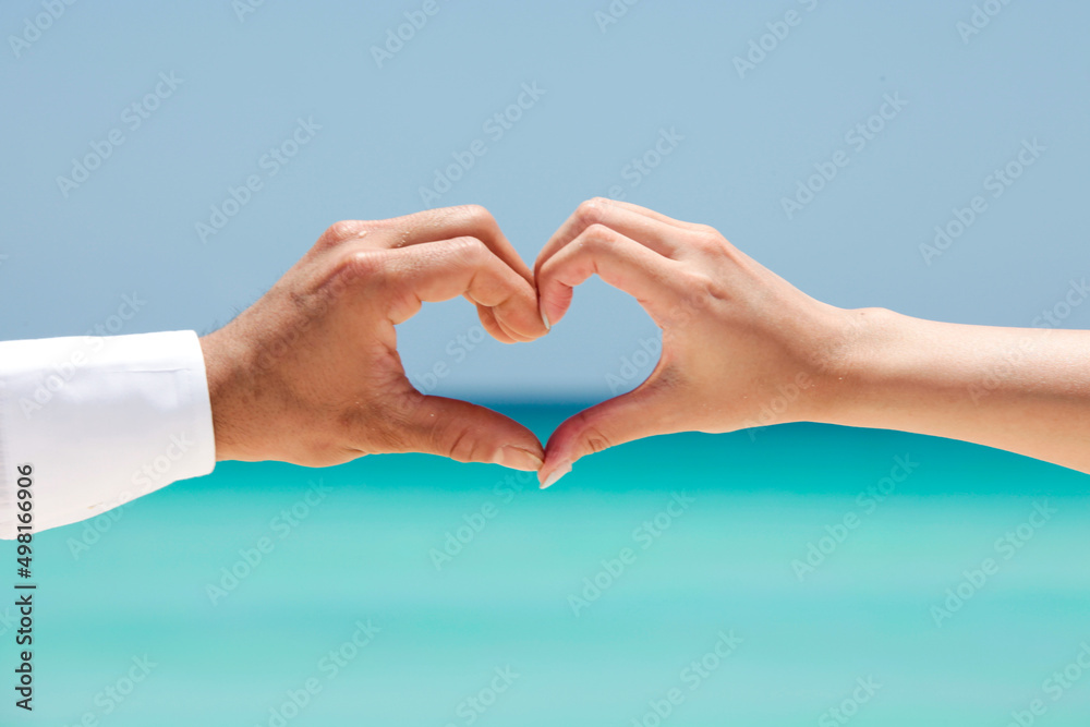 Fototapeta premium ウエディングフォトの砂浜をバックに手で幸せを表現した写真