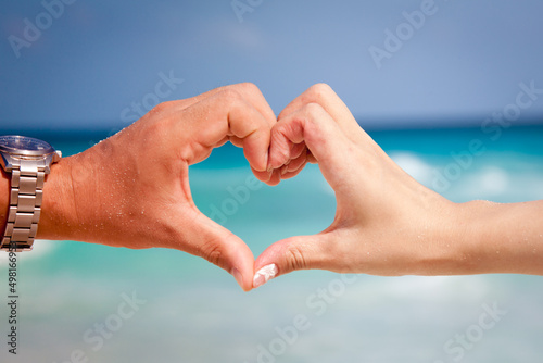ウエディングフォトの砂浜をバックに手で幸せを表現した写真