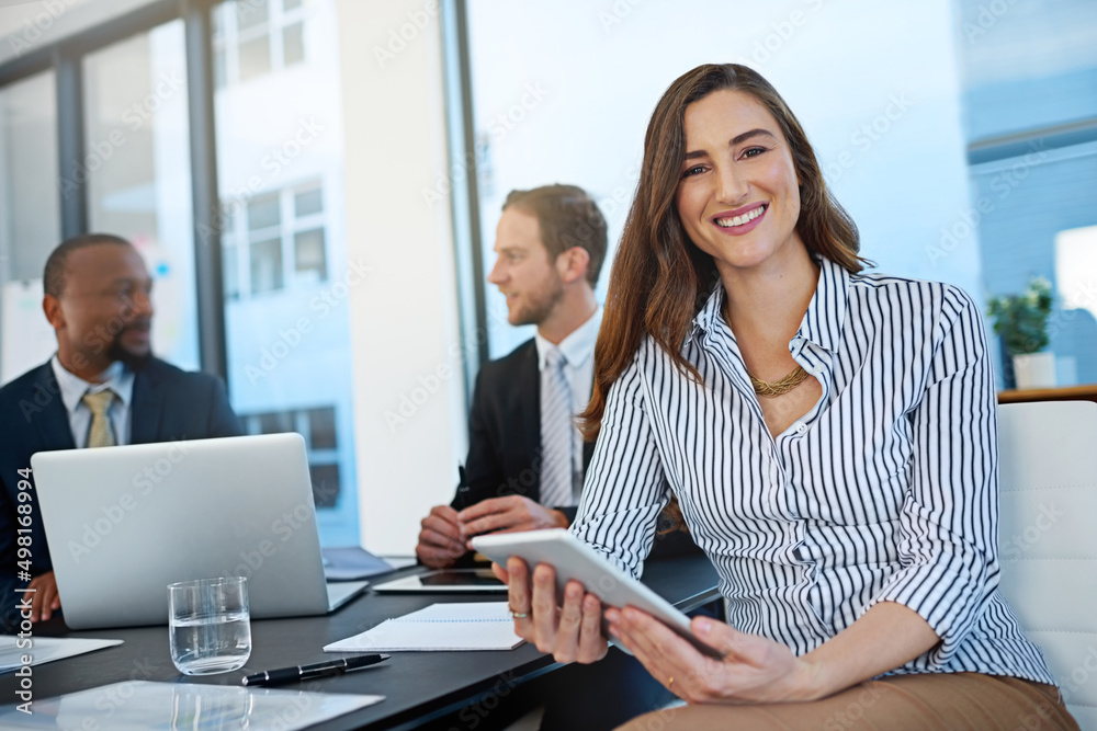 Our team is geared toward success. Portrait of a young businesswoman working in the boardroom with her colleagues in the background. Our team is geared toward success. Portrait of a young businesswoman working in the boardroom with her colleagues in the background.