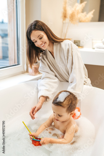 Tela Caring mother bathing her baby in the bathroom