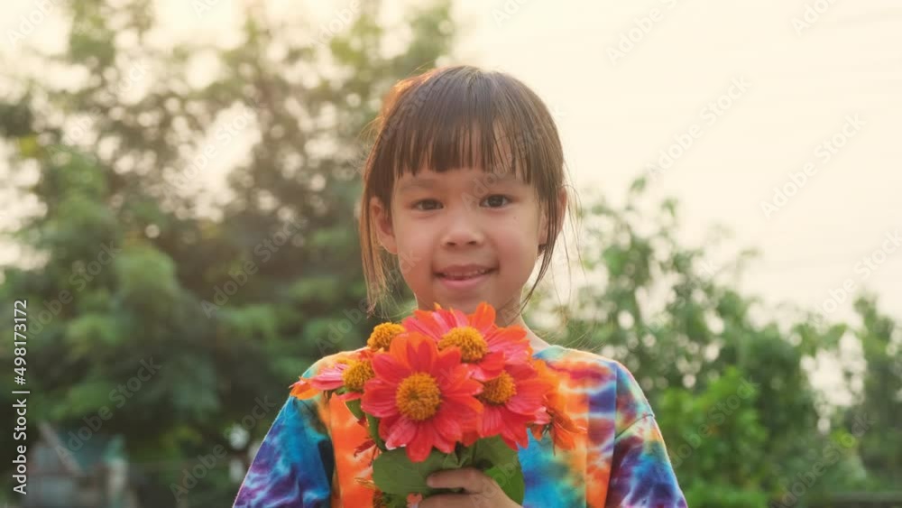 Portrait of a cute little girl with a spring bouquet on a sunny summer evening. Smiling girl holding a bouquet of fresh orange flowers in her hand.