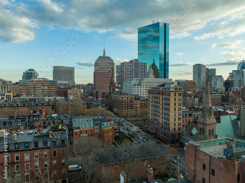 Aerial afternoon view of brown stone apartment buildings and glass high-rise sky scraper in elegant downtown Boston neighborhood with cloudy blue sky