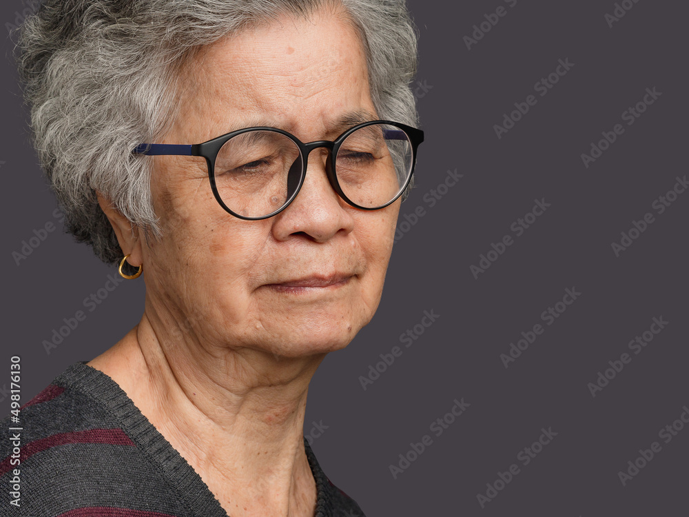 Senior woman looking away with face show serious while standing on gray background