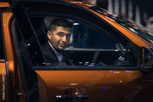 businessman in a car in motor show or car showroom looking for new car to buy